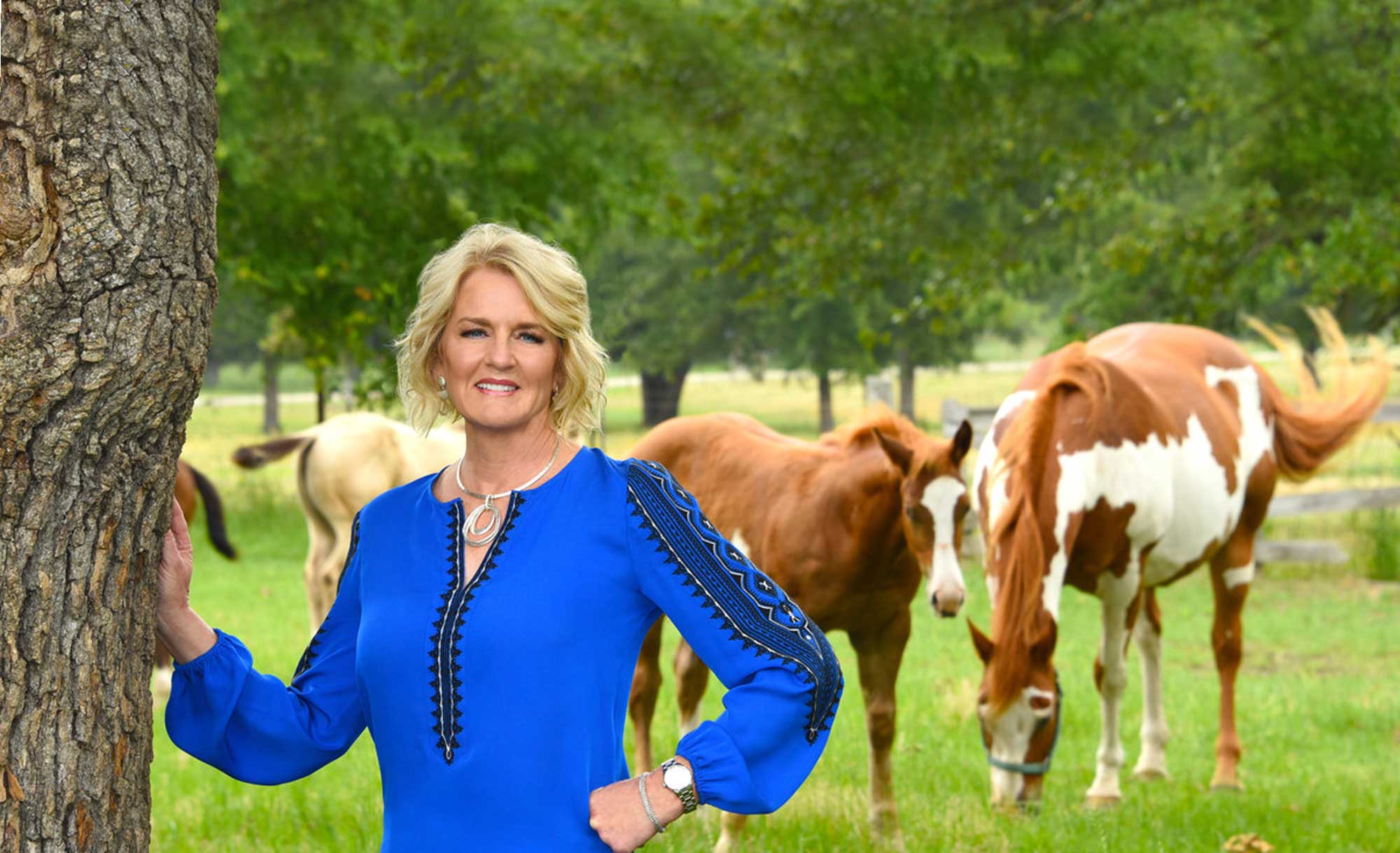 Mica Pryor standing in front of horses in a blue top